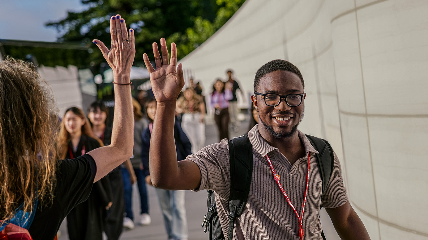 El ganador del Swift Student Challenge saluda a un asistente durante la WWDC en Apple Park.