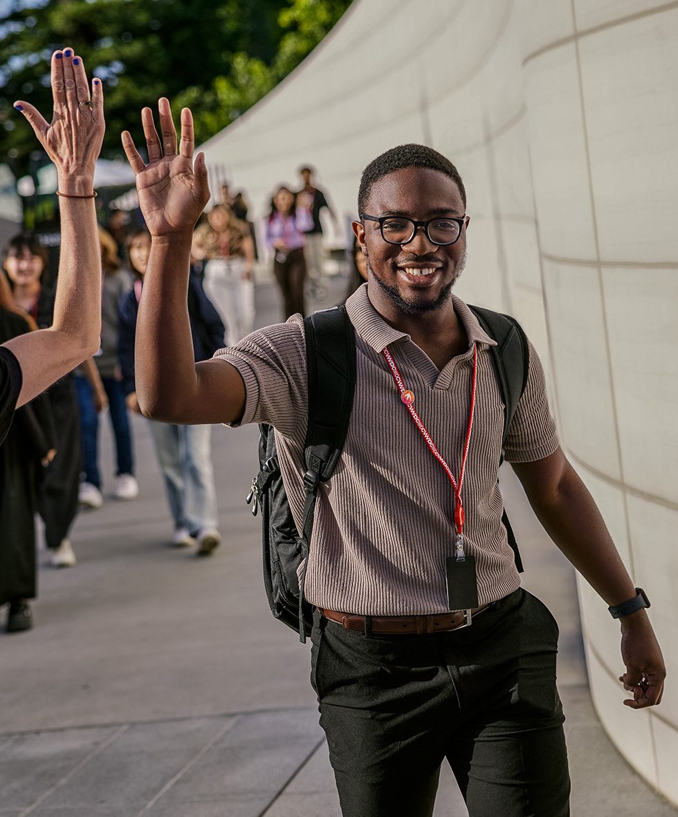 Swift Student Challenge winner high-fives an attendee during WWDC at Apple Park.