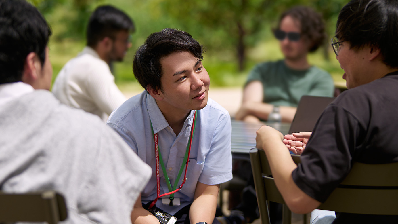 Swift Student Challenge winner engages in conversation with fellow attendees outdoors at WWDC.