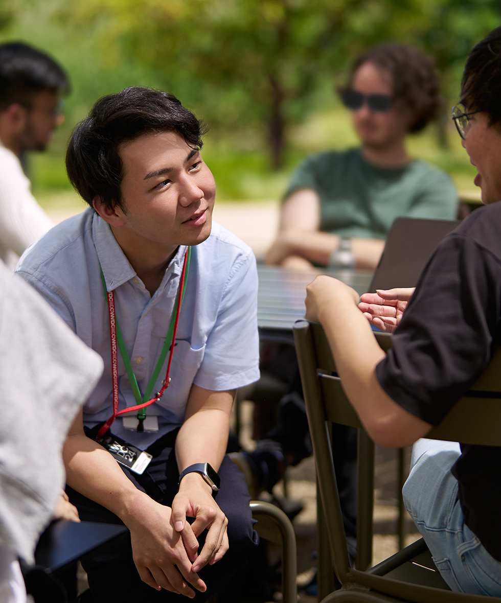 Swift Student Challenge winner engages in conversation with fellow attendees outdoors at WWDC.