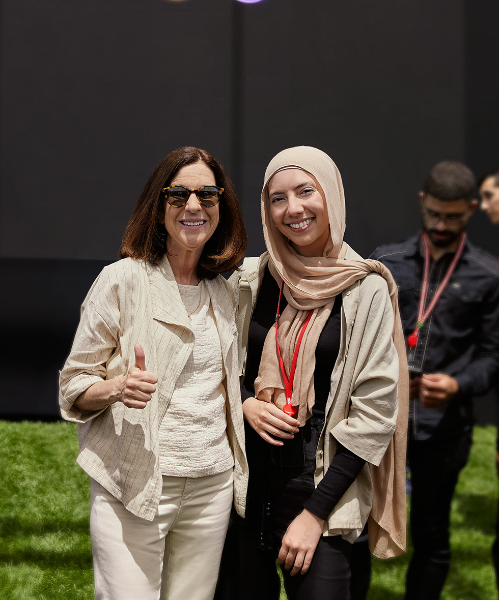 Eine Gewinnerin der Swift Student Challenge posiert bei der WWDC mit einer Mentorin im Apple Park.