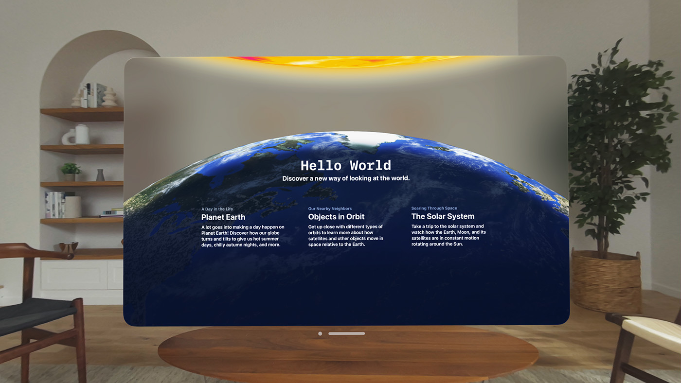A screenshot of the Hello World app on Apple Vision Pro. The screenshot appears front and center in a tidy living room with white walls, light wood furniture, a plant, and a set of shelves. The Hello World app clearly shows an image of Earth underneath an image of the sun and offers three categories: Planet Earth, Objects in Orbit, and The Solar System.
